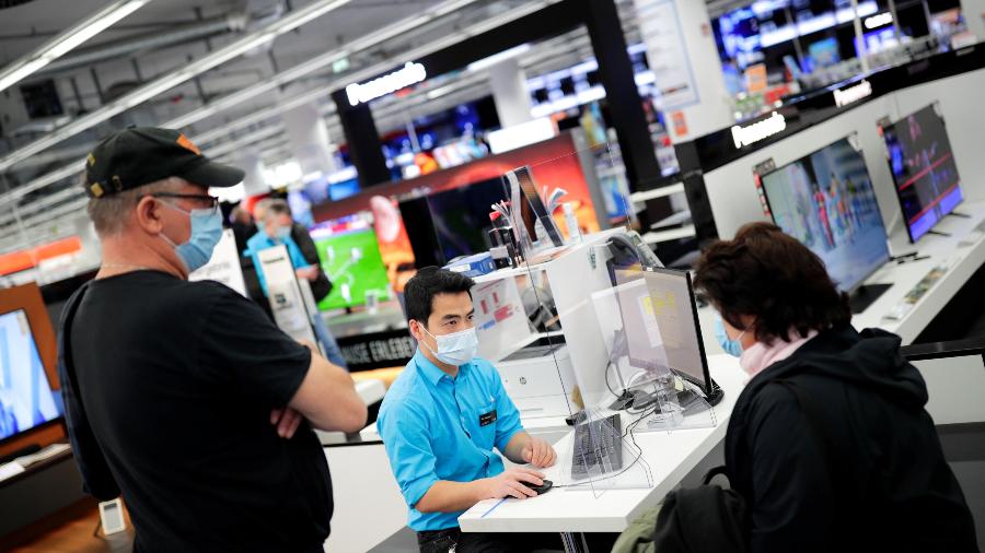 Atendente em loja de eletrônicos auxilia cliente em loja em Berlim. O governo alemão flexibilizou as restrições para o comércio - REUTERS/Hannibal Hanschke