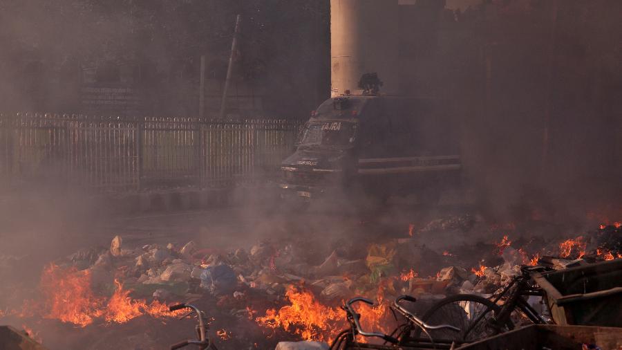 25.fev.2020 -  Um veículo da polícia passa por detritos queimados que foram incendiados por manifestantes na Índia - Danish Siddiqui/Reuters