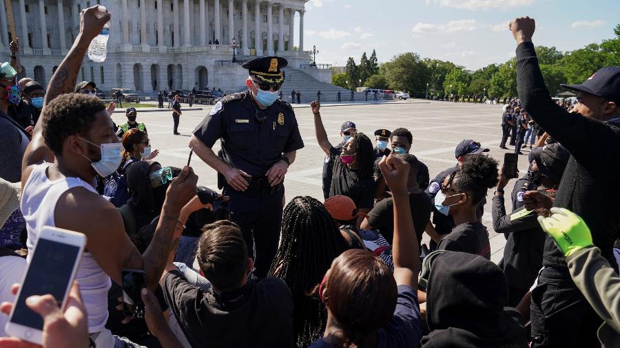 Manifestantes se ajoelham na frente de um policial para protestar contra a morte na custódia policial de George Floyd, no Capitólio dos EUA em Washington - KEVIN LAMARQUE/REUTERS