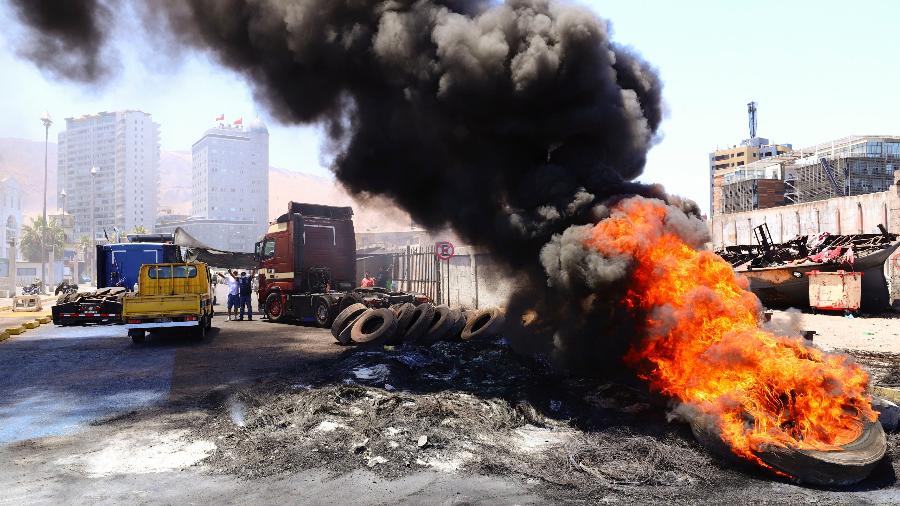 13.fev.22 - Pneus queimam em uma estrada de acesso ao porto de Iquique (Chile), que permanece bloqueado durante uma greve nacional organizada por caminhoneiros contra o assassinato de um colega de trabalho - Ignacio Munoz/AFP