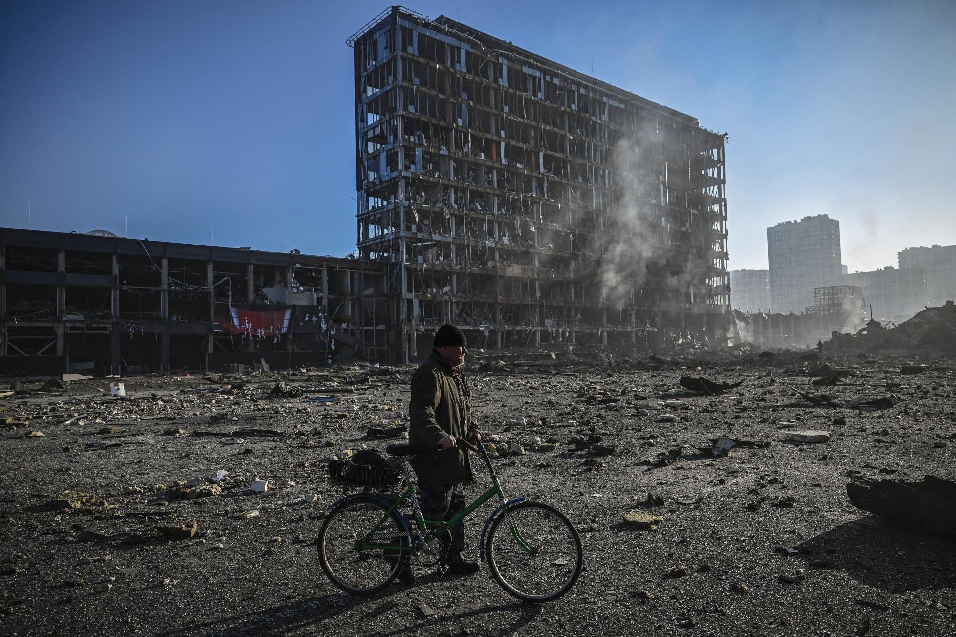 March 21, 2022 - A man rides a bicycle near the rubble outside the Retroville shopping center in a residential area that was destroyed after the Russian attack on the Ukrainian capital Kiev - March 21, 2022 - Aris Messinis/AFP