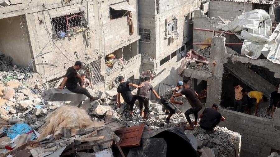 Palestinos verificam os escombros de uma casa após o bombardeio israelense em Nuseirat, no centro da Faixa de Gaza, em 16 de setembro de 2024 - EYAD BABA/AFP