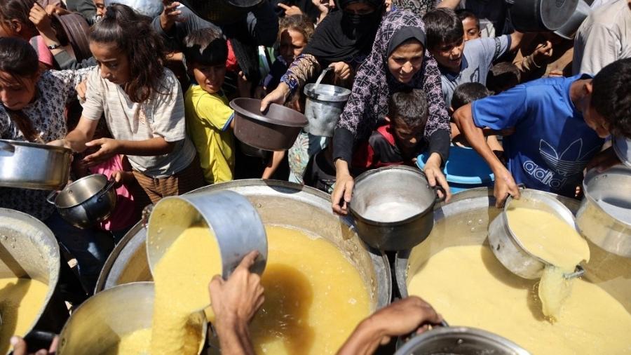 Palestinos recebem sopa em um ponto de distribuição de alimentos na cidade de Gaza, em 1 de agosto de 2025