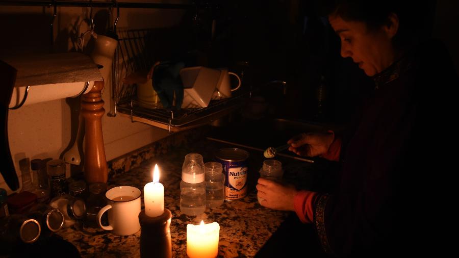 Mulher prepara leite sob a luz de velas, em Montevidéu, durante apagão que deixou o Uruguai e a Argentina sem energia na manhã deste domingo - Miguel Rojo/AFP