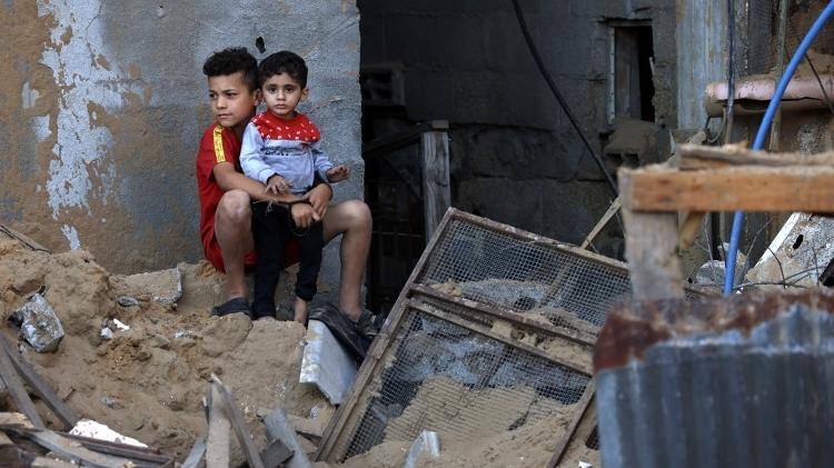 Crianças palestinas em meio a escombros após ataque de Israel a campo de refugiados em Rafah, no sul da Faixa de Gaza