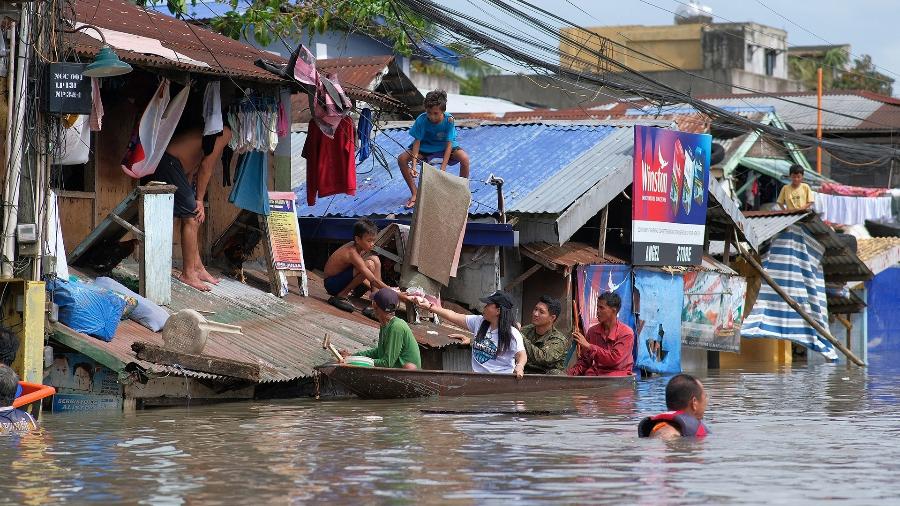 Pessoas em um bote navegam por área inundada pela tempestade tropical Trami - ZALRIAN SAYAT / AFP