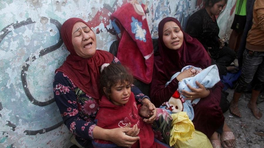 Mulheres e crianças palestinas choram após abrigo para refugiados em escola ser atingido por bombardeio israelense na Cidade de Gaza