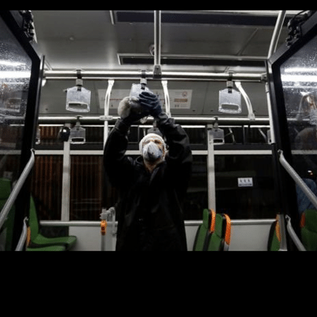 Um funcionário limpa uma das alças de apoio em um ônibus no Irã - AFP