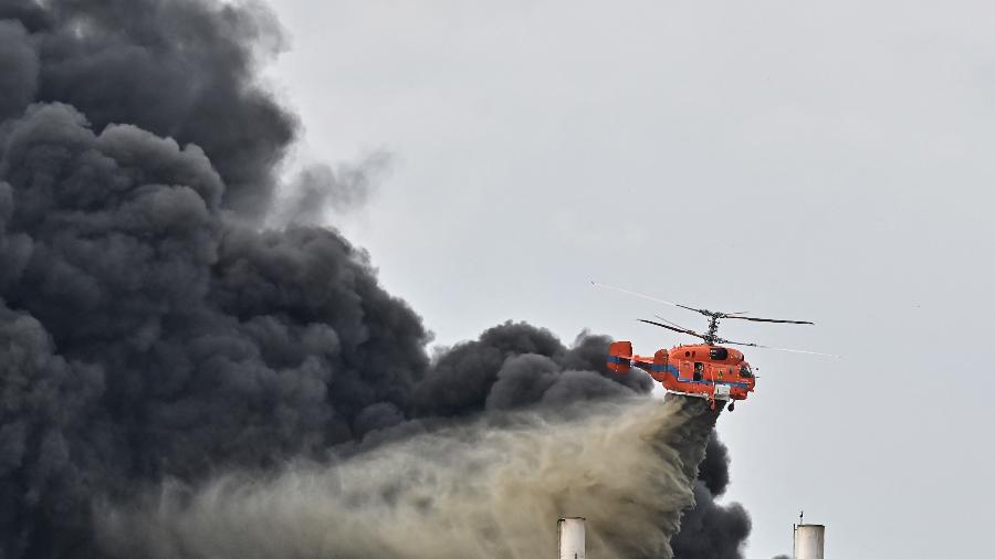 Helicóptero despeja água no local de uma explosão e incêndio em uma fábrica de plásticos nos arredores de Bangcoc - Lillian Suwanrumpha/AFP