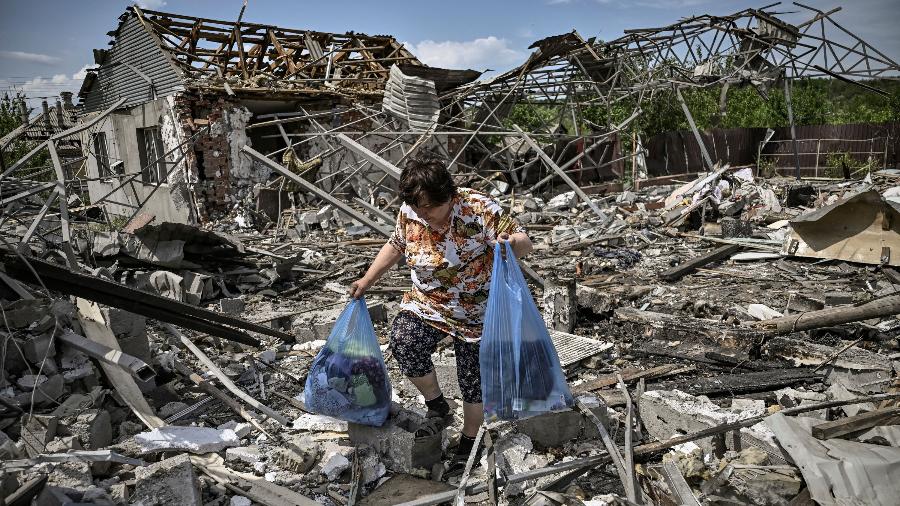 1º.jun.2022 - Mulher recolhe pertences nos destroços de sua casa depois que um ataque atingiu área residencial na cidade de Sloviansk, no leste da Ucrânia - 1º.jun.2022 - Aris Messinis/AFP