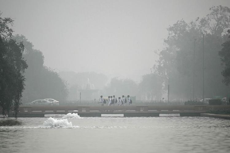 Crianças são vistas no horizonte em meio à neblina causada por poluição em Nova Déli, na Índia