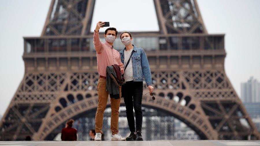 16.mai.2020 - Pessoas usando máscara de proteção enquanto tiram foto em frente à Torre Eiffel, em Paris, na França - Gonzalo Fuentes/Reuters