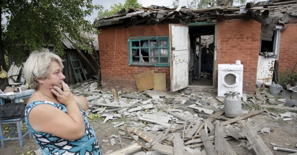 16.ago.2015 - Moradora observa casa que foi danificada em bombardeio nos arredores de Donetsk, no leste da Ucrânia. Mais de 845 militares ucranianos figuram como desaparecidos em combate após 16 meses de conflito armado no leste do país, informou neste domingo Irina Geraschenko, membro da delegação de Kiev no processo de paz de Minsk