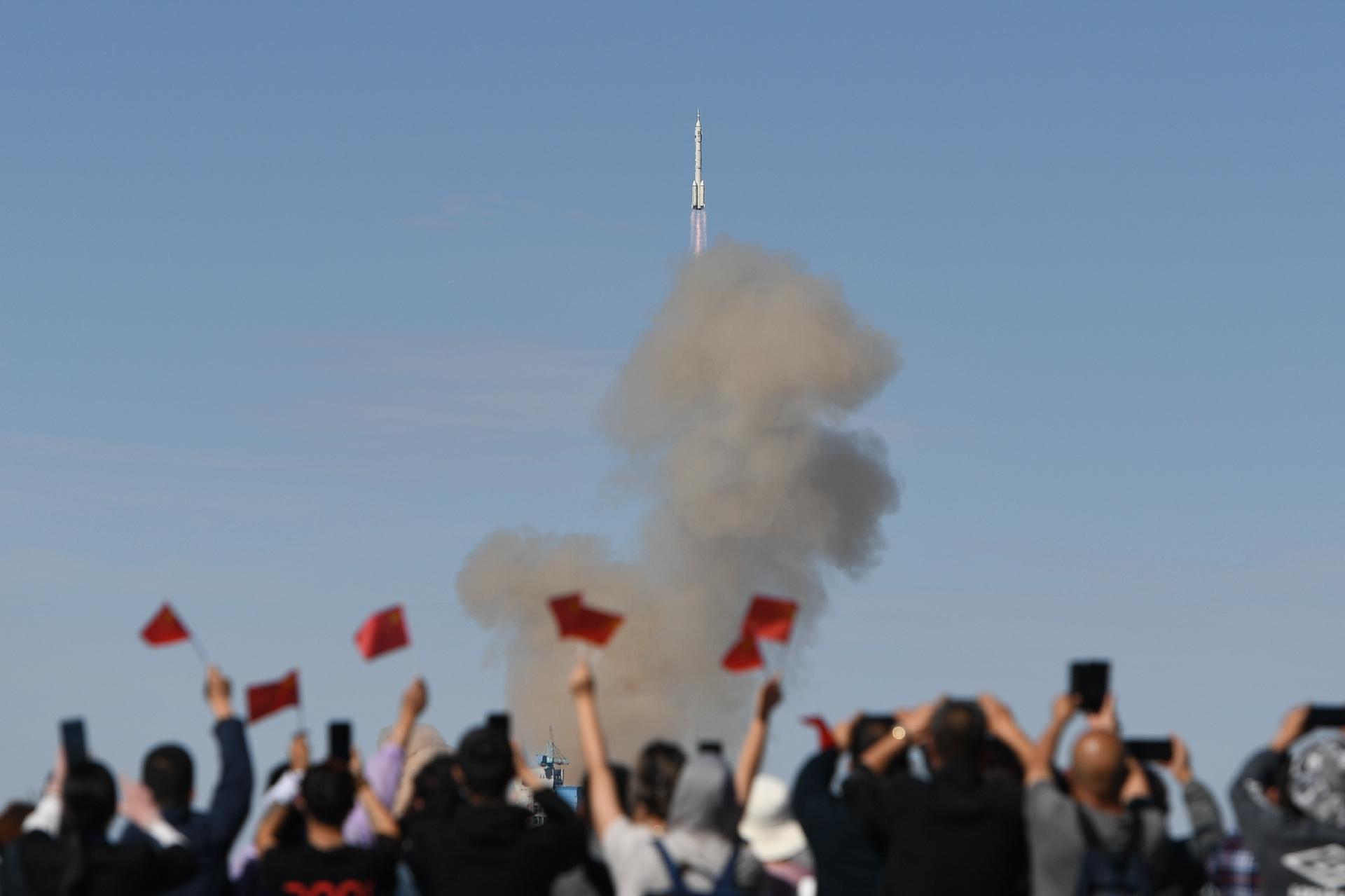 Pessoas assistem e comemoram o lançamento da nave espacial tripulada Shenzhou-12, nas proximidades do Centro de Lançamento de Satélites de Jiuquan, no noroeste da China, em 17 de junho de 2021 - Xinhua/Liu Lei