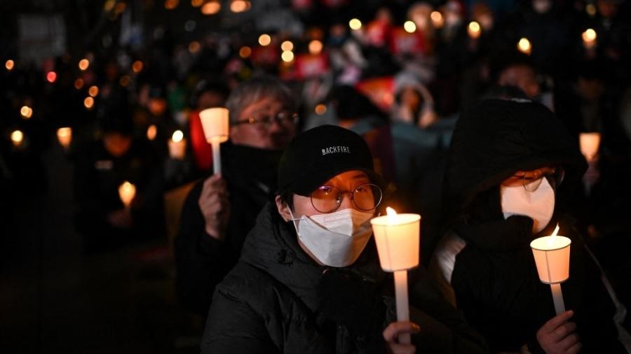 Pessoas participam de uma vigília à luz de velas enquanto protestam contra o presidente da Coreia do Sul, Yoon Suk Yeol, em Seul, em 4 de dezembro de 2024