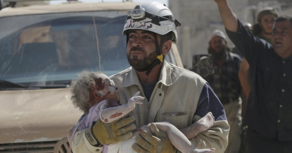 20.out.2015 - Membro da Defesa Civil carrega um bebê ferido que sobreviveu após ficar soterrado em um local atingido por um ataque aéreo de forças leais ao ditador sírio Bashar Assad, na cidade de Marshamsha, sul da Síria