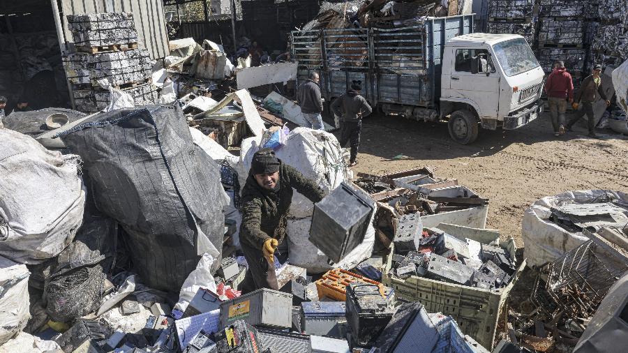 Um palestino pega baterias descartadas para revender para reciclagem, em um ferro-velho em Khan Yunis, no sul da Faixa de Gaza, em 14 de fevereiro de 2022 - Said Khatib/AFP