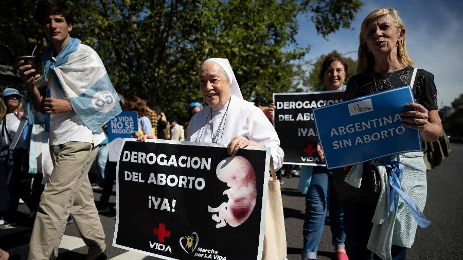 Manifestantes seguram placa com pedidos para revogar o aborto legal durante protesto em Buenos Aires