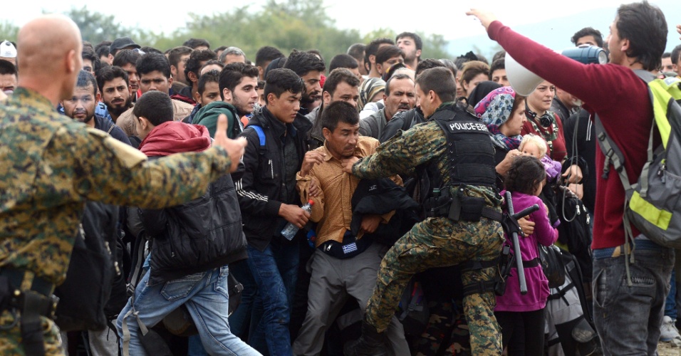 19.out.2015 - Policiais controlam entrada de refugiados em um acampamento na cidade de Gevgelija, na Macedônia, próxima a fronteira com a Grécia. Refugiados vindos principalmente da Síria chegam à Europa na tentativa de salvar suas vidas ao fugirem da guerra civil síria