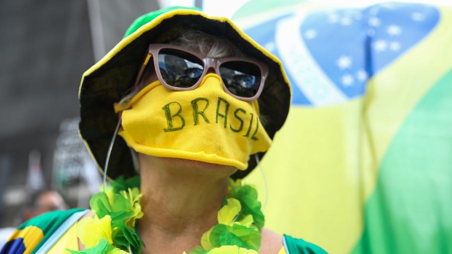 Mulher veste cores do Brasil e usa máscara durante pandemia do novo coronavírus - Alexandre Schneider/Getty Images