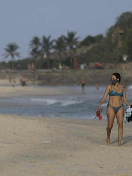 Casal com máscara de proteção caminha na praia do Arpoador, no Rio de Janeiro - 