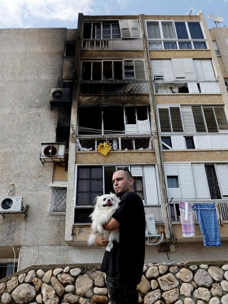Homem segura cachorro no colo em Israel após disparos vindos da Faixa de Gaza