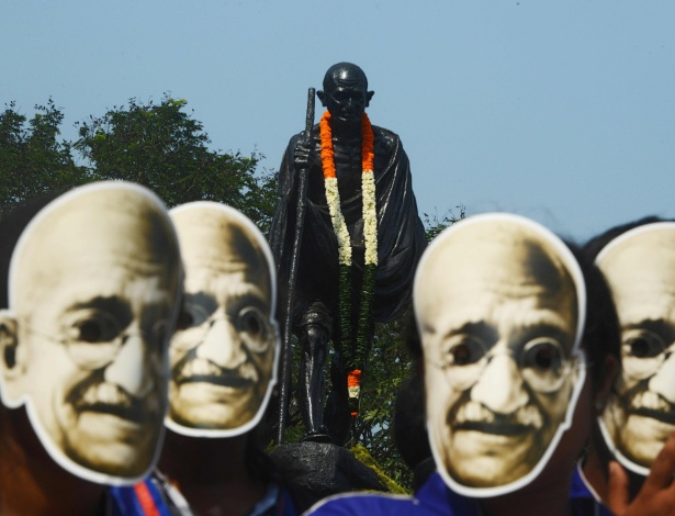 Estudantes indianos usam máscaras de Mahatma Gandhi para celebrar os 150 anos de seu nascimento - AFP