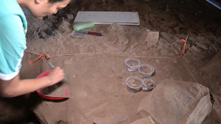 Arqueóloga limpa com um pincel objetos e restos mortais encontrados no solo coberto por fuligem  - Arquivo Pessoal