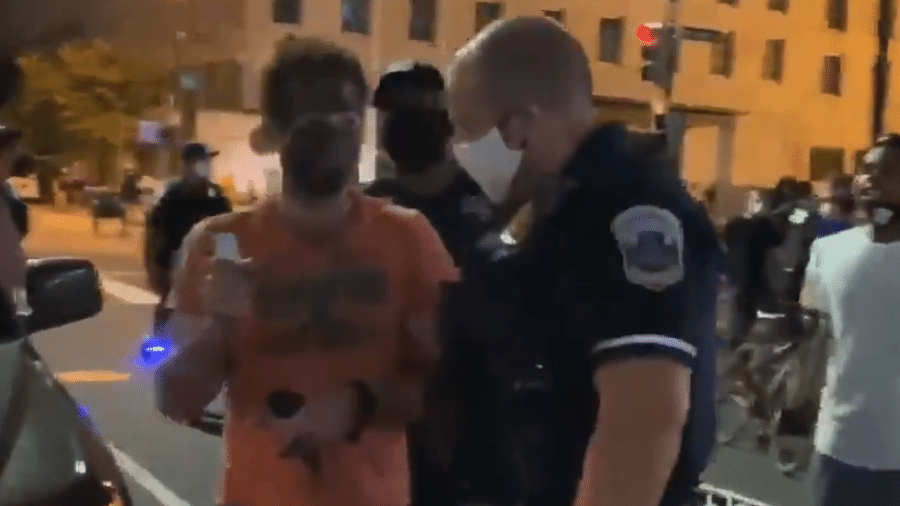 Policial tenta retirar um homem branco que usava blackface em um protesto antirracista em Washington, nos EUA. Ele acabou agredido por um manifestante - Reprodução/Twitter