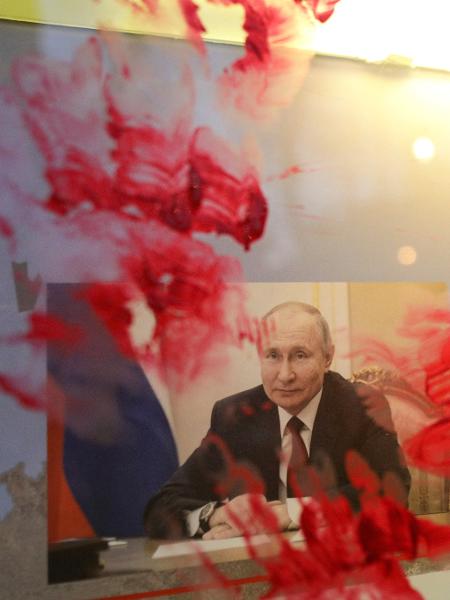 Retrato de Putin é manchado com tinta vermelha durante protesto do lado de fora da Embaixada da Rússia, em Bucareste, na Romênia