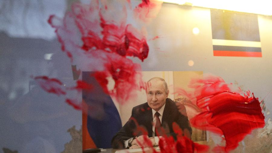 Retrato de Putin é manchado com tinta vermelha durante protesto do lado de fora da Embaixada da Rússia, em Bucareste, na Romênia - Inquam Photos/Reuters