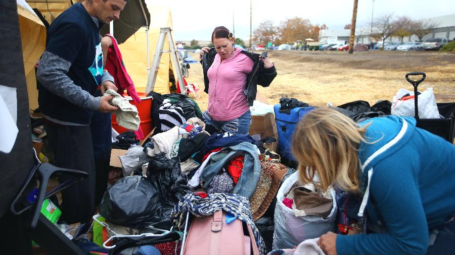 Voluntários e evacuados deslocados por incêndio avaliam roupas doadas em um acampamento improvisado perto de um Walmart em Chico, Califórnia - Jim Wilson/The New York Times