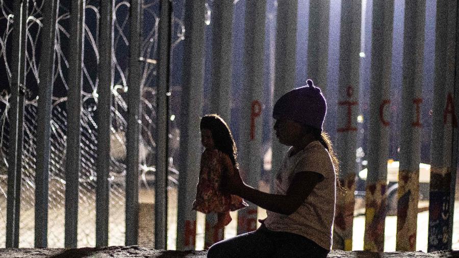 Garota da Guatemala próxima junto à cerca da fronteira entre EUA e México, na cidade de Tijuana - Guillermo Arias / AFP