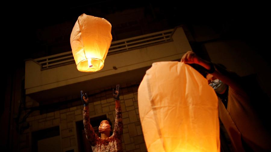Pessoas usam máscaras enquanto acendem lanternas de papel em memória daqueles que morreram devido ao surto da covid-19 em San Giorgio, Itália - ALESSANDRO GAROFALO/REUTERS