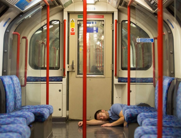 Homem dorme no chão do vagão do metrô londrino no primeiro dia do "Night Tube" - Daniel Leal-Olivas/AFP