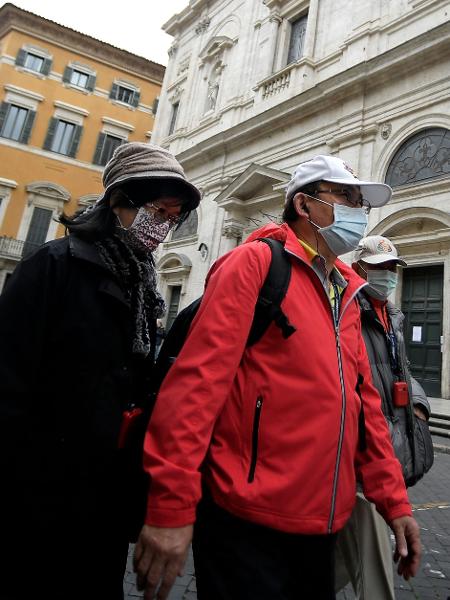Usando máscaras, turistas asiáticos passam em frente à Igreja San Luigi dei Francesi, em Roma, fechada por conta do novo coronavírus - Filippo Monteforte/AFP