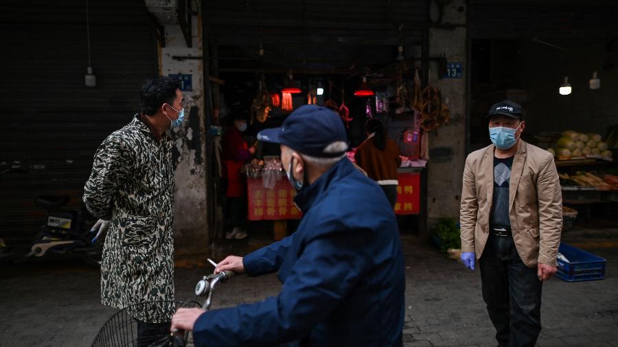 Homem anda de bicicleta em Wuhan, cidade da China onde a pandemia do novo coronavírus teve início - Hector RETAMAL / AFP