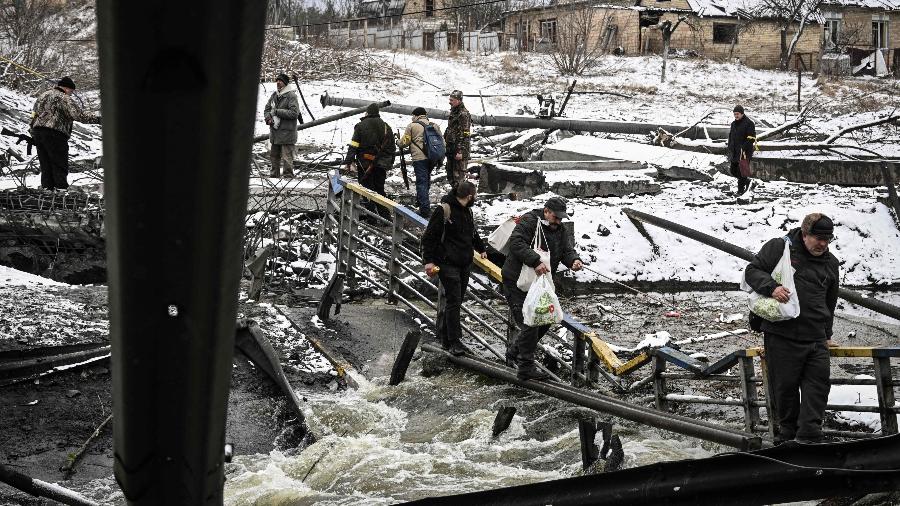 Civis tentam cruzar rio em ponte destruída por bombardeios desta terça (1º) em Kiev, capital da Ucrânia - Aris Messinis/AFP