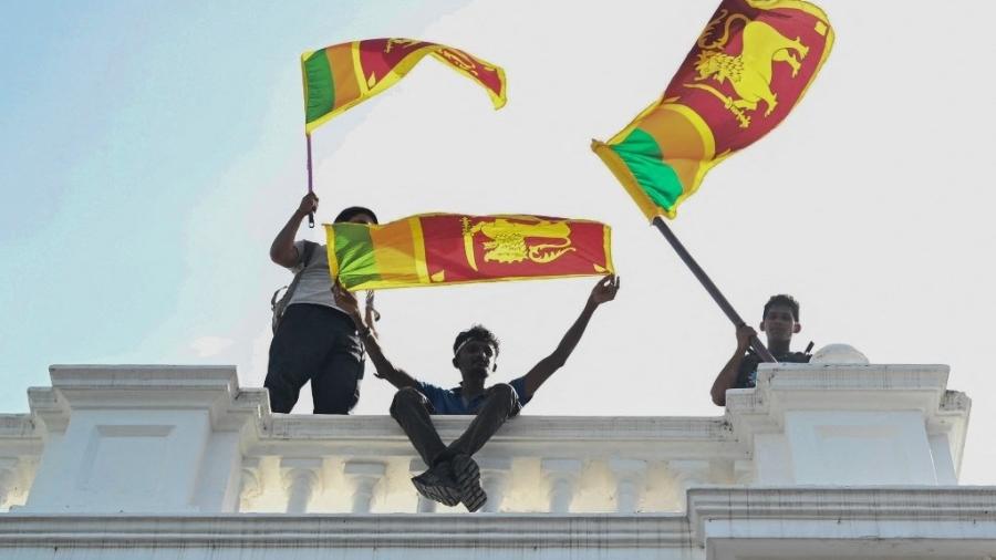 Manifestantes com bandeiras do Sri Lanka na sacada do gabinete do primeiro-ministro, em Colombo - Arun Sankar/AFP