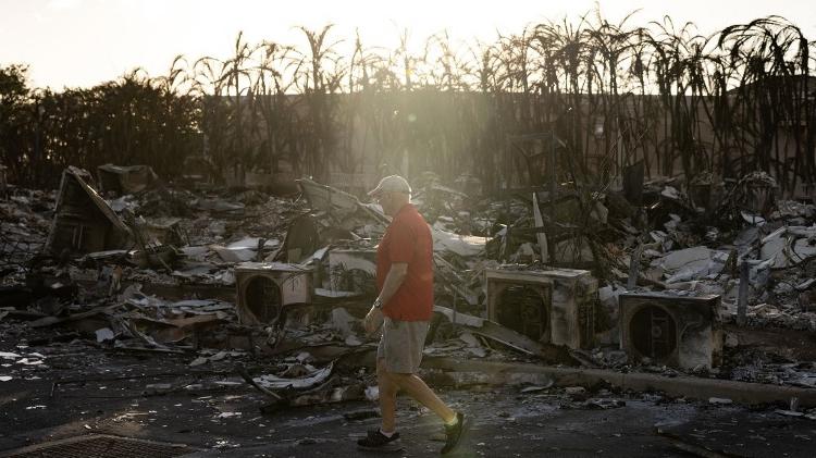 Morador caminha entre os destroços do incêndio no Havaí