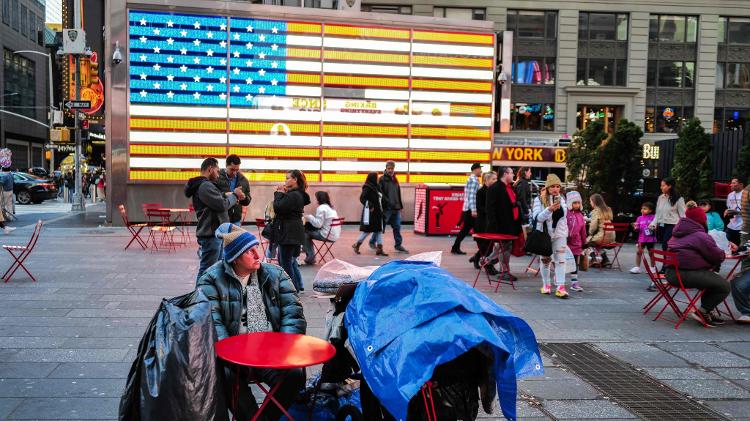 Sem-teto sentado à mesa na Times Square, em Manhattan, Nova York, em abril de 2024