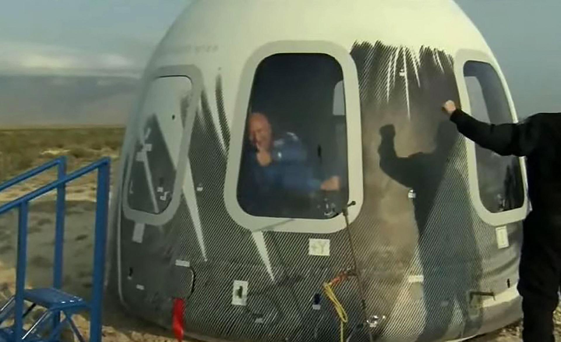 Jeff Bezos acena de dentro da cápsula da Blue Origin indicando que deu tudo certo no voo espacial - Blue Origin/AFP