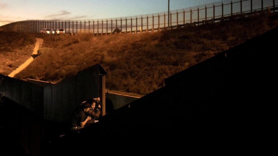3.dez.2018 - Migrantes da América Central tentam pular a cerca que separa as cidades de Tijuana e San Diego, na fronteira do México com os Estados Unidos; no fundo, oficiais de patrulha da fronteira norte-americana - REUTERS/Alkis Konstantinidis 