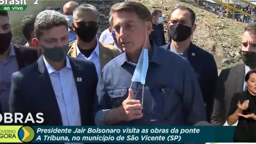 O presidente Jair Bolsonaro (sem partido) tira máscara ao visitar a Ponte dos Barreiros, em São Vicente, no litoral paulista - Reprodução