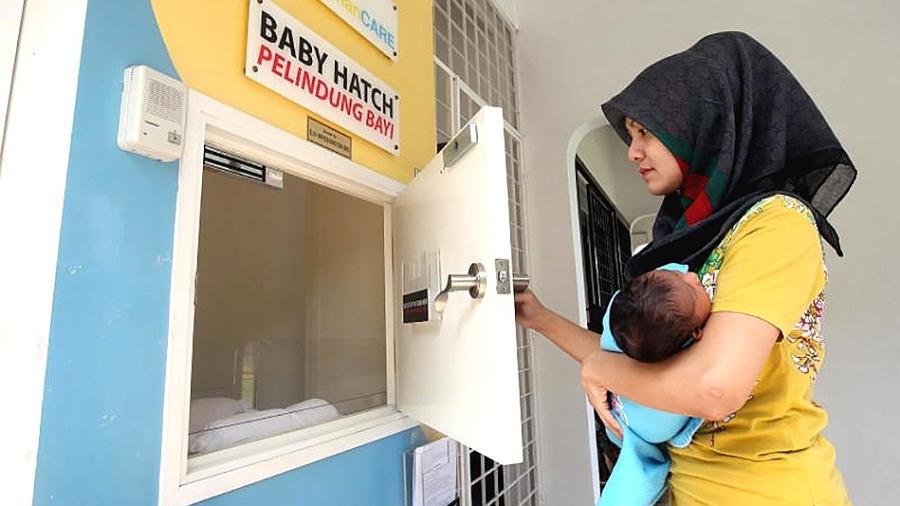 Funcionária da OrphanCare demonstra como colocar um bebê no depositório - Azhar Mahfof/The Star