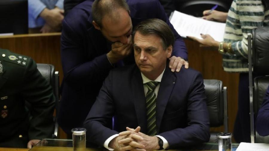Deputado Eduardo Bolsonaro, à época do PSL-SP, cochicha ao ouvido do pai, o então presidente Jair Bolsonaro, durante sessão solene na Câmara. Sempre teve a pretensão de ser um pensador que enxerga o futuro... Deputado Eduardo Bolsonaro, à época do PSL-SP, cochicha ao ouvido do pai, o então presidente Jair Bolsonaro, durante sessão solene na Câmara. Sempre teve a pretensão de ser um pensador que enxerga o futuro...