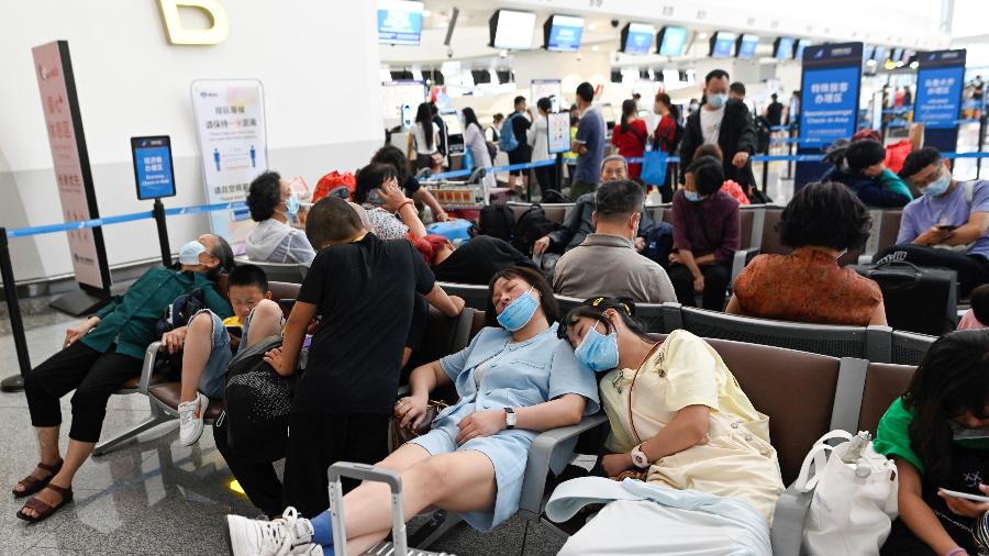 Passageiros descansam enquanto esperam por seus voos no Aeroporto Internacional de Pequim após centenas serem cancelados por chuvas torrenciais e ventos fortes  - Wang Zhao/AFP