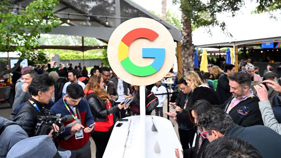 Logotipo do Google com jornalistas em volta mexendo em lançamentos do Google I/O, evento da empresa realizado em Mountain View, na Califórnia - Josh Edelson/AFP