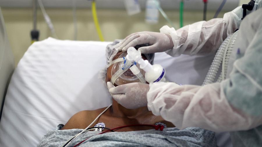 Fisioterapeuta ajusta máscara de oxigênio em paciente com Covid-19 em hospital de São Paulo - Amanda Perobelli/Reuters