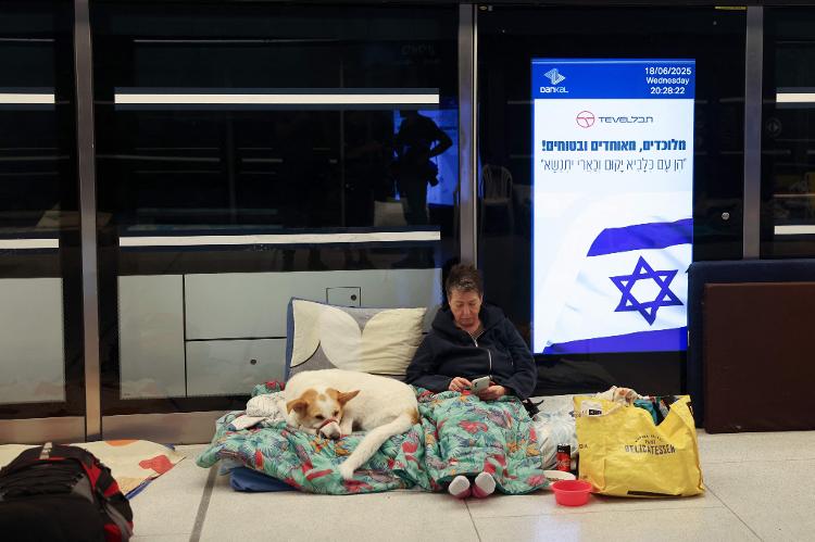 18.jun.2025 - Uma mulher acompanhada de seu cachorro se abriga para passar a noite em uma estação subterrânea de trem leve na cidade de Ramat Gan, a leste de Tel Aviv, em Israel 18.jun.2025 - Uma mulher acompanhada de seu cachorro se abriga para passar a noite em uma estação subterrânea de trem leve na cidade de Ramat Gan, a leste de Tel Aviv, em Israel